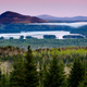 A view of Attean Pond near Jackman, Maine, with mountains in the background and fog over a valley below.